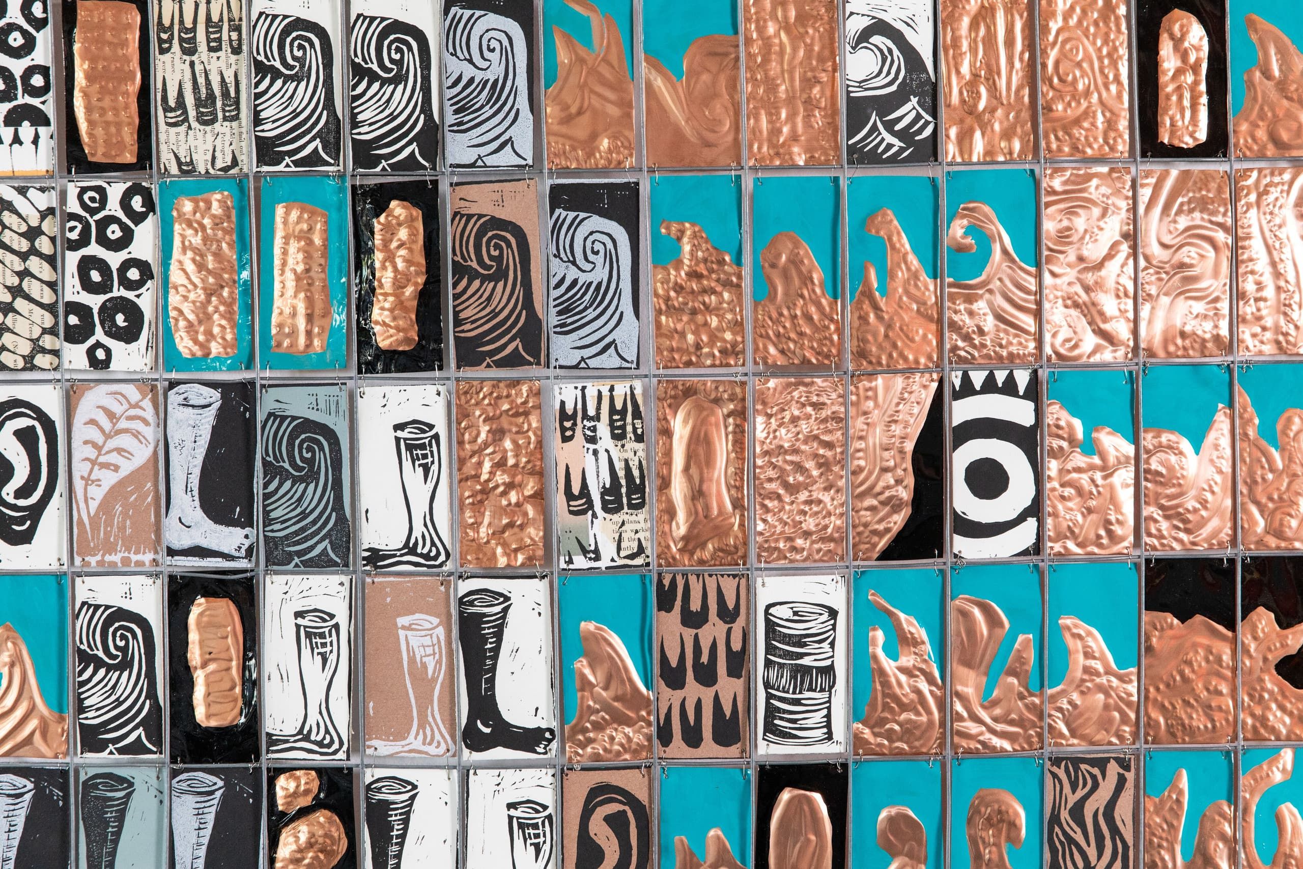 A grid-based wall installation composed of small tiles alternating between copper-textured reliefs, black and white drawings, and teal backgrounds creating a modular artistic pattern.